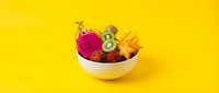 Fresh tropical fruit bowl with dragon fruit, kiwi and pineapple on bright yellow background for healthy eating and nutrition concepts.