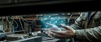 Worker's hands holding glowing digital data hologram over industrial machinery, representing technology integration, automation, and smart manufacturing solutions for business operations.