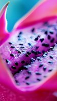 Vibrant macro shot of dragon fruit slice showing juicy pink flesh and black seeds against turquoise background, creating abstract natural patterns and textures.