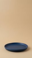 Empty blue ceramic plate on neutral beige background, isolated product shot for tableware, dinnerware, kitchenware, and home decor design projects.