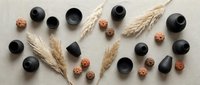 Flat lay composition with black ceramic bowls, wheat ears and walnuts arranged on neutral textured background for kitchen and food styling projects.