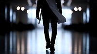 Silhouette of person walking in dark corridor with dramatic lighting and reflective floor, creating mysterious atmospheric mood for crime or thriller concepts.