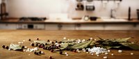 Scattered white pearls and dark beads with dried botanical elements on wooden floor in modern kitchen setting, suitable for styling and design projects.