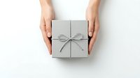 Female hands holding elegant gray gift box with ribbon bow on white background, perfect for holiday celebrations and special occasions.