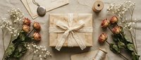 Elegant gift wrapping flat lay with dried roses, baby's breath flowers, kraft paper package with lace bow, twine and natural decorative elements.