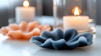 Decorative blue ceramic flower-shaped dish with peachy blooms and lit candles in glass holders, creating a serene spa or home decor arrangement for relaxation and wellness styling.