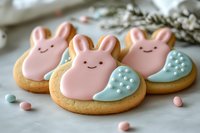 Pink bunny sugar cookies decorated with royal icing and mint green accents on white background, homemade Easter treats with cute smiling faces.