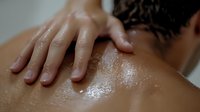 Close up of hands performing therapeutic massage on oiled back and shoulders during spa treatment, showing relaxation and wellness techniques for stress relief.