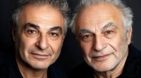 Portrait of two senior Caucasian men with gray hair smiling at camera against dark background. Professional headshot showing confidence and wisdom. Suitable for business or lifestyle.