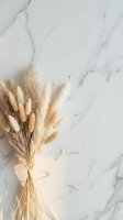 Dried pampas grass bouquet tied with ribbon on white marble surface with natural lighting and scattered petals for home decor and styling projects.