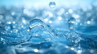 Macro shot of water drops and splashes creating dynamic shapes against blurred blue background with bokeh effect. Pure freshness concept for wellness and nature.