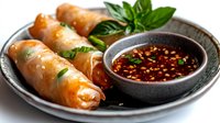 Crispy golden spring rolls served with spicy chili dipping sauce and fresh basil garnish on dark plate for Asian cuisine and appetizer concepts.