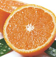 Fresh juicy orange cut in half showing detailed pulp segments and natural texture with water drops on green leaf, macro food photography for healthy eating concept.