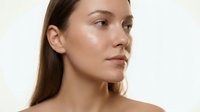 Woman with long brown hair and fair complexion in profile view against neutral background, showcasing skincare and cosmetics for beauty and wellness marketing.