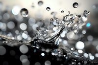 Macro photography of water droplet splash creating crown shape with bokeh background effect. Elegant liquid dynamics captured in monochrome tones.