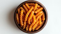 Golden crispy crinkle cut french fries in rustic wooden bowl on white background, top view of fresh hot potato strips with textured wavy surface.