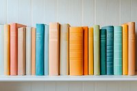 Colorful hardcover books arranged in a row on white shelf, showcasing pastel and vibrant spines in orange, blue, green, and yellow tones.