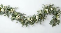 Elegant eucalyptus garland with white roses and delicate flowers on clean background for wedding decor, events, and botanical design projects.