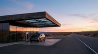 Modern minimalist gas station with sleek architecture and wooden overhang at sunset, featuring parked vehicle on desert highway with expansive landscape views for travel and automotive concepts.