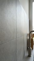 Modern gray textured wall tiles in contemporary bathroom interior with brass faucet fixture creating elegant minimalist design for home renovation projects.