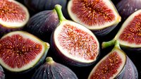 Fresh ripe purple figs cut in half showing juicy red flesh and seeds on dark background, macro food photography for cookbook or restaurant menu.