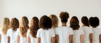 Diverse group of women showing various natural hair textures and styles from behind, wearing white shirts against neutral background for hair care concepts.