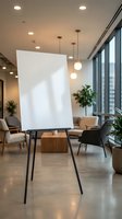 Blank white flipchart easel in modern office meeting room with pendant lights and plants ready for business presentation or training session.