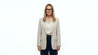 Professional woman with blonde hair and glasses wearing beige cardigan over white blouse and dark pants, isolated on white background for corporate and business design use.