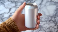 Female hand in brown knit sweater holding blank aluminum beverage can against marble background, mockup for branding and product presentation.