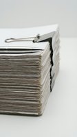 Thick stack of paper documents held with a binder clip and a silver pen on top, symbolizing paperwork, bureaucracy, and office work.