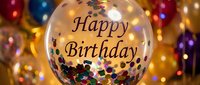 Transparent balloon with Happy Birthday text filled with colorful confetti, surrounded by festive gold and multicolored balloons at a celebration.