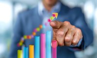 Caucasian businessman pointing at colorful ascending bar graph with upward arrow showing growth trend and success in business analytics.