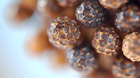 Macro view of metallic copper spherical beads with textured surface pattern and reflective details against blurred background. Luxury jewelry design elements.