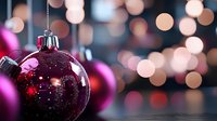 Shiny magenta and burgundy ornaments with glitter hanging against blurred bokeh lights, perfect for holiday and festive season decorations.