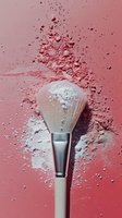 Makeup brush with scattered pink loose powder on coral background, creating dynamic splash effect for cosmetic and beauty industry advertising.