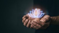 Glowing lotus flower floating above cupped hands in dark setting symbolizing spirituality, meditation, enlightenment and inner peace for wellness concepts.
