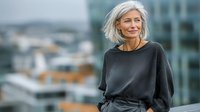 Confident mature Caucasian businesswoman with silver hair smiling outdoors in urban setting. Professional lifestyle portrait for corporate marketing materials.