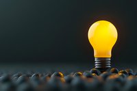 Glowing yellow light bulb emerging from dark pebbles against black background, symbolizing bright ideas, innovation and creative breakthrough in business.