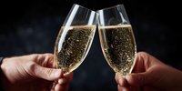 Two hands toasting with champagne flutes filled with sparkling wine against dark background for celebration events and luxury lifestyle concepts.