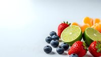Fresh mixed berries and citrus fruits arranged on white background for healthy eating and nutrition concepts.