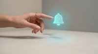 Hand pointing at glowing blue notification bell icon floating above wooden surface representing digital alerts and communication technology.