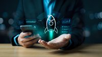 Business professional holding smartphone with holographic rocket launch icon and digital data analytics interface for startup growth and innovation concepts.