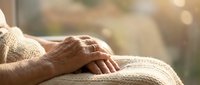 Elderly hands resting peacefully on knitted blanket in warm sunlight. Senior care, comfort, relaxation, aging gracefully, cozy home atmosphere, healthcare concept.
