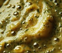 Creamy herb sauce with bubbles and texture, close-up macro shot showing rich consistency for gourmet cooking applications.