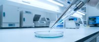 Laboratory pipette dispensing sample into petri dish in modern medical research facility with advanced equipment and sterile environment for scientific analysis.