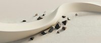 Crushed dark chocolate pieces scattered on neutral surface with curved white ceramic dish, minimalist food styling and composition.