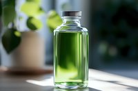 Clear glass bottle filled with bright green liquid against blurred natural background, sunlight creating luminous glow through transparent container.