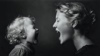 Joyful moment between mother and child with matching expressions of laughter against dark background, capturing pure emotional connection.