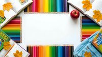 Colorful pencils frame blank white paper with autumn leaves and red apple for back to school creative projects and educational activities.