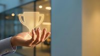 Female hand holding glowing golden trophy cup in modern office environment, symbolizing success, achievement, and business victory for corporate recognition and award concepts.